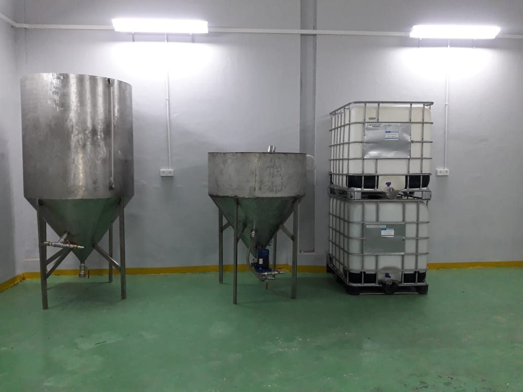 Two conical reactor vessels beside storage tanks in the Batam workshop
